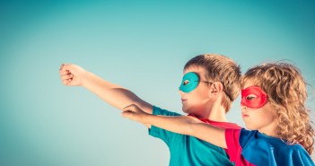 Superhero children against summer sky background. Kids having fun outdoors. Boy and girl playing. Success and winner concept