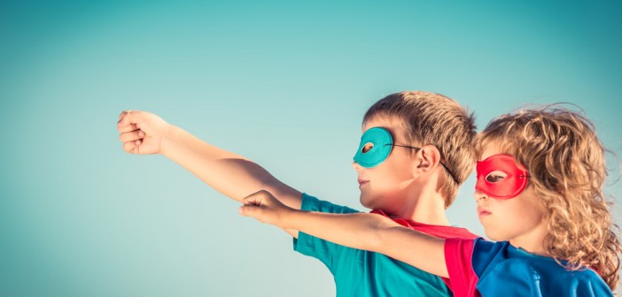 Superhero children against summer sky background. Kids having fun outdoors. Boy and girl playing. Success and winner concept