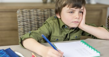 boy doesn't feel like making homework with hand under his head