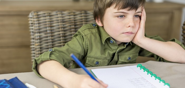 boy doesn't feel like making homework with hand under his head