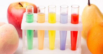 Fruit close chemical test tubes. Genetic Engineering. pesticides in foods. White background.